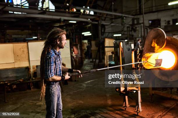 glass blower smoking a cigarette and working at furnace in a glass factory - blowgun stock pictures, royalty-free photos & images