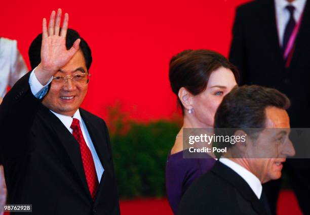 Chinese President Hu Jintao waves goodbye to journalists while French President Nicolas Sarkozy and his wife Carla Bruni-Sarkozy walk past during a...