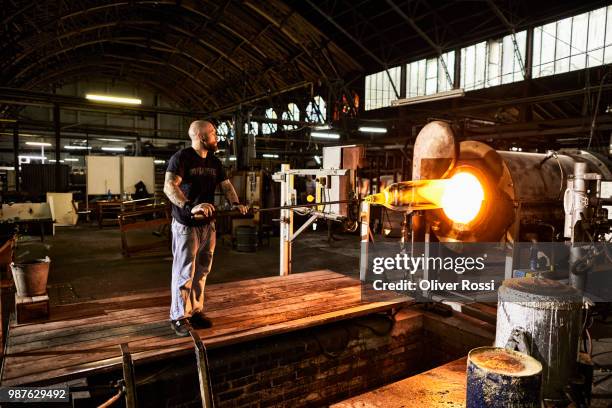 glass blower working at furnace in a glass factory - blowgun stock pictures, royalty-free photos & images