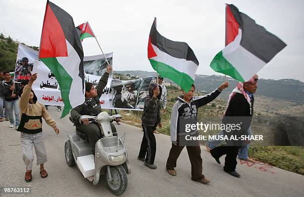 Palestinian boy rides a scooter and holds his national flag during a demonstration by Palestinians and foreign peace activists against Israel's...
