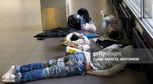 Stranded passengers rest on the floor of Amsterdam Schiphol airport, on April 19, 2010. The volcano ash cloud over Europe is draining the coffers of...