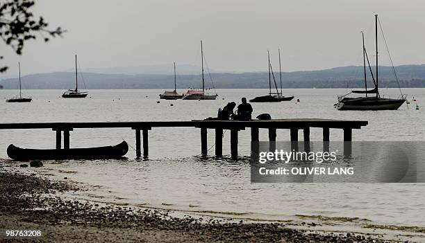 People sit on a pier at Lake Ammer in the southern German town of Stegen on April 29, 2010. Meteorologists are forecasting cooler and wetter weather...