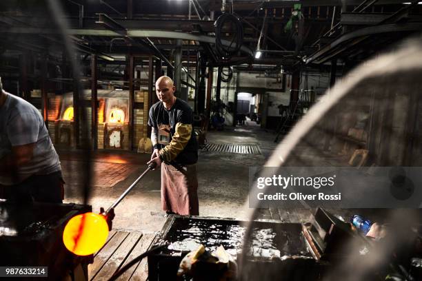 glass blower working with blowpipe on glowing glass in glass factory - blowgun stock pictures, royalty-free photos & images