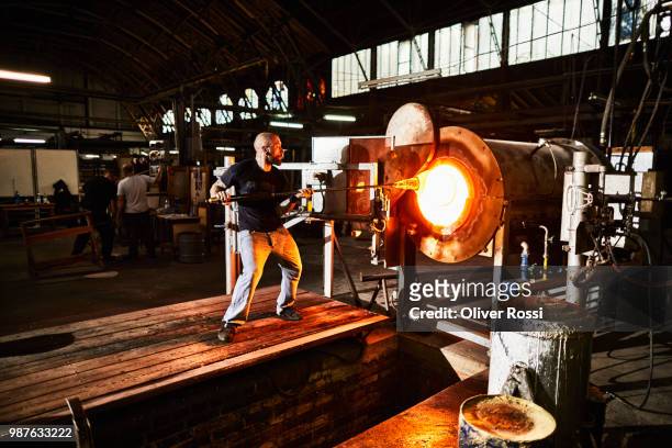 glass blower working at furnace in a glass factory - glass factory stock-fotos und bilder