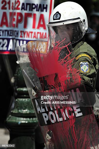 Riot police member whose shield is splattered in red paint looks on during a demonstration in central Athens on April 22, 2010. Greek civil servants...