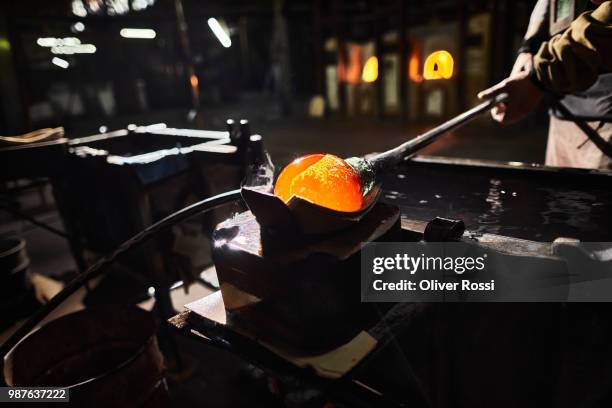 close-up of glass blower working on glowing glass in glass factory - blowgun stock pictures, royalty-free photos & images