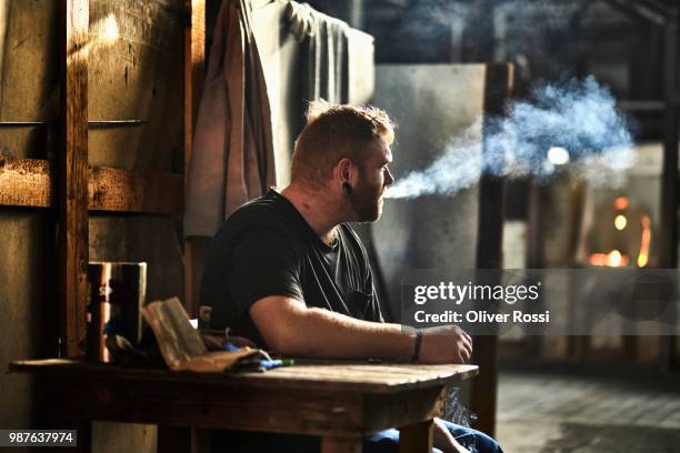 worker having a break smoking a cigarette in a foundry - foundry worker stock pictures, royalty-free photos & images