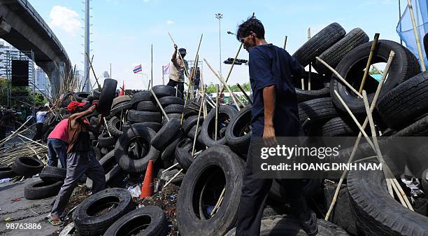 Thai Red-Shirt anti-government protesters place used truck tyres and sharpened bamboo sticks to build up a new barricade after they accepted to move...