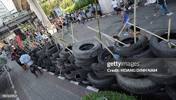 Thai Red-Shirt anti-government protesters place used truck tyres and sharpened bamboo sticks to build up a new barricade after they accepted to move...