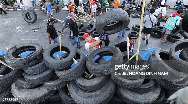 Thai Red-Shirt anti-government protesters place used truck tyres and sharpened bamboo sticks to build up a new barricade after they accepted to move...