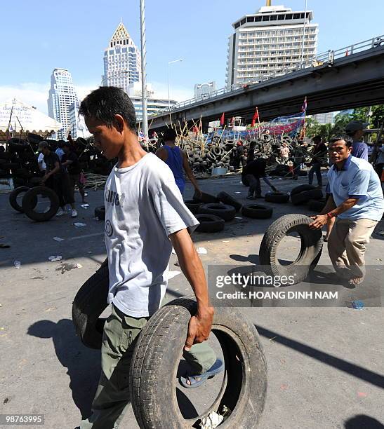 Thai Red-Shirt anti-government protesters carry used truck tyres as they build up a new barricade after accepting to move back their main barricade...