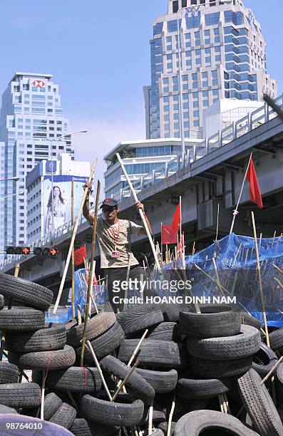 Thai Red-Shirt anti-government protester stand atop a pile of used truck tyres as his comrades build up a new barricade after accepting to move back...