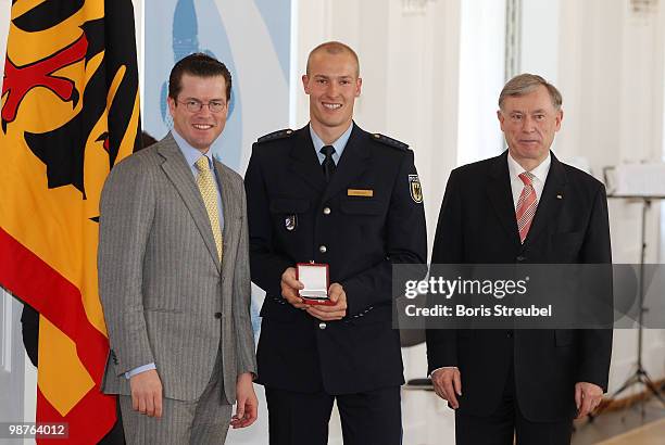 German President Horst Koehler and German Defense Minister Karl-Theodor zu Guttenberg pose with bobsled driver David Moeller at the Silbernes...