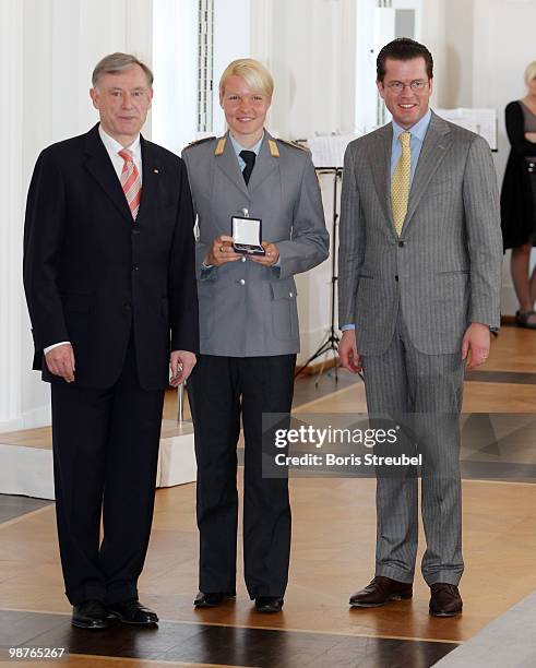 German President Horst Koehler and German Defense Minister Karl-Theodor zu Guttenberg pose with the German speed skater Stephanie Beckert at the...