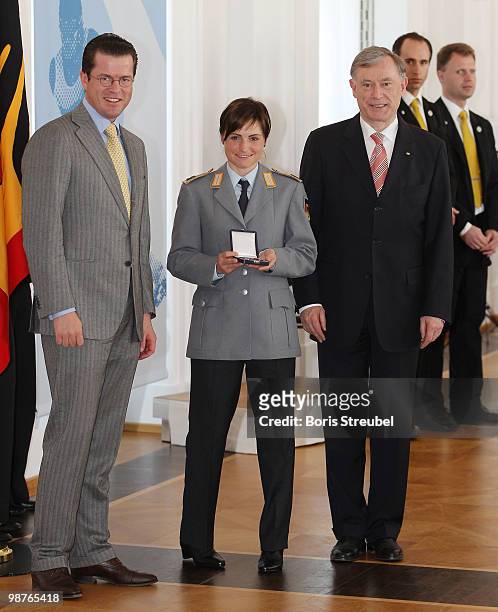 German President Horst Koehler and German Defense Minister Karl-Theodor zu Guttenberg pose with German biathlete Andrea Henkel at the Silbernes...