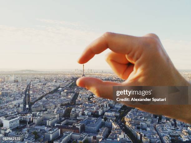 man pretending to hold eiffel tower with his fingers, paris, france - small stockfoto's en -beelden