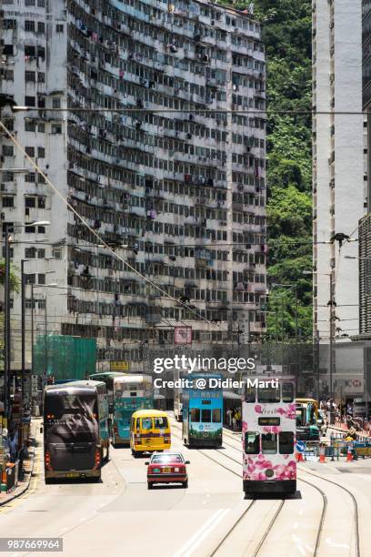 tramway, cars and buses drive by a large apartment block in the north point residential district in hong kong island - didier marti stock pictures, royalty-free photos & images