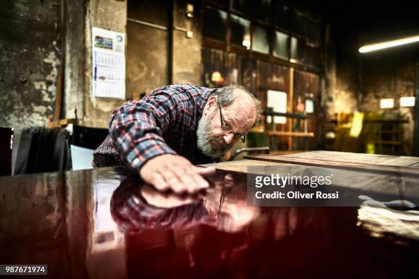 senior man in a glass factory examining glass pane - glass factory stock-fotos und bilder