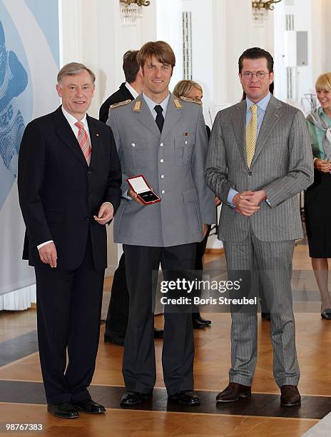 German President Horst Koehler and German Defense Minister Karl-Theodor zu Guttenberg pose with the cross country skier Axel Teichmann at the...