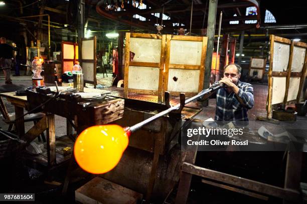 glass blower working with blowpipe on glowing glass in glass factory - glass blowing stock pictures, royalty-free photos & images