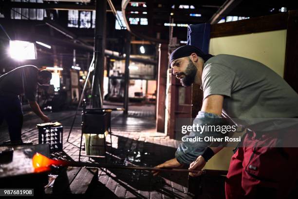 glass blower working on glowing glass in glass factory - blowgun stock pictures, royalty-free photos & images