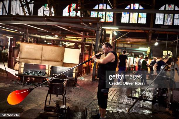 glass blower working with blowpipe on glowing glass in glass factory - glass blowing - fotografias e filmes do acervo