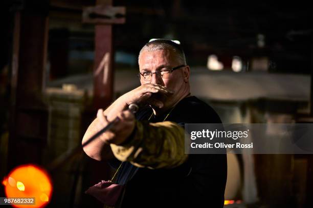 glass blower working with blowpipe on glowing glass in glass factory - glass blowing stockfoto's en -beelden