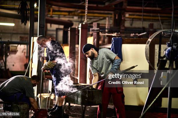 glass blower working with blowpipe on glowing glass in glass factory - blowgun stock pictures, royalty-free photos & images