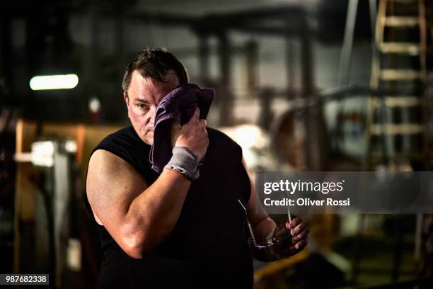 exhausted worker having a break in a factory wiping off sweat - sudan fotografías e imágenes de stock