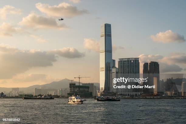 an helicopter flying over the victoria harbor in hong kong with the skyscrapers of kowloon in the background - didier marti stock pictures, royalty-free photos & images