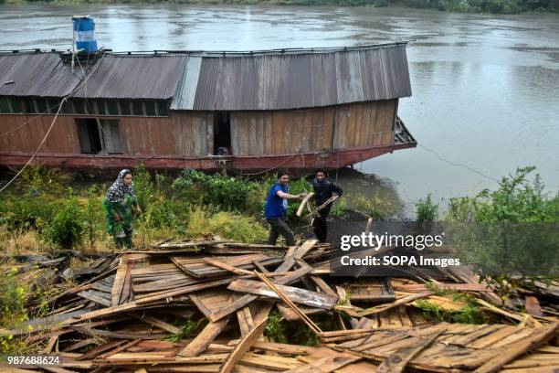 Family members collect the left overs from the houseboat, which capsized following heavy rains. A flood alert has been sounded in Kashmir in the wake...