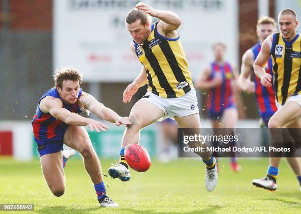 Jonathan Haidon of Sandringham kicks the ball from Cal Searle of Port Melbourne during the round 13 VFL match between Port Melbourne and Sandringham...