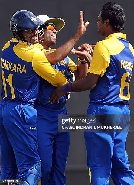 Sri Lankan cricketer Lasith Malinga is congratulated by teammates Kumar Sangakkara and Angelo Mathews after he took the catch of Brendon McCullam of...