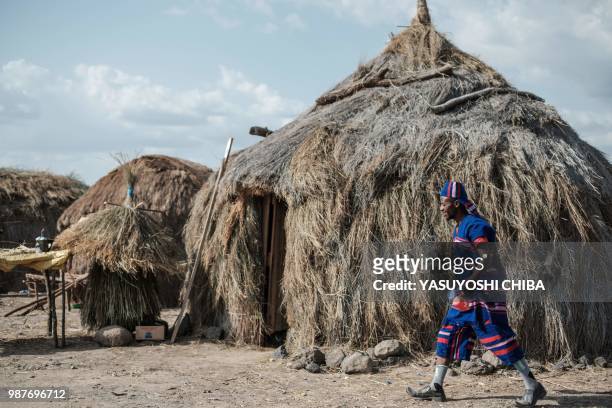 Man of the Burji tribe walks past houses part of installations showing traditional homes during the 11th Marsabit Lake Turkana Culture Festival in...