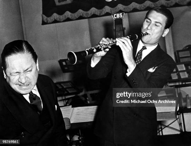 Jazz clarinettist and bandleader Artie Shaw clowns around with humorist Robert Benchley during a performance on Old Gold's Radio Program circa 1940...