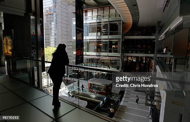 Woman looks over shoppers from a balcony in The Shops at Columbus Circle, an upscale mall, April 30, 2010 in New York, New York. The US economy grew...