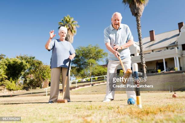 senior mannen leende med klubba i hand slå bollen spelar krocket - krocketklubba bildbanksfoton och bilder