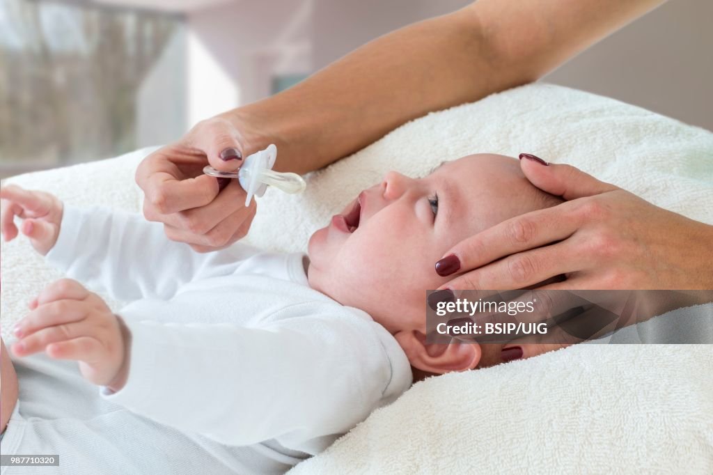 Mother giving a pacifier to her baby.
