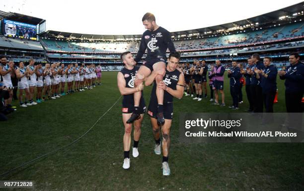 Kade Simpson of the Blues is chaired from the field after his 300th match by teammates Marc Murphy and Ed Curnow during the 2018 AFL round15 match...