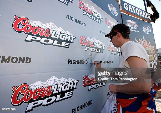 Kyle Busch, driver of the M&M's Toyota, autographs the Coors Light pole award board after he qualified first for the NASCAR Sprint Cup Series Crown...