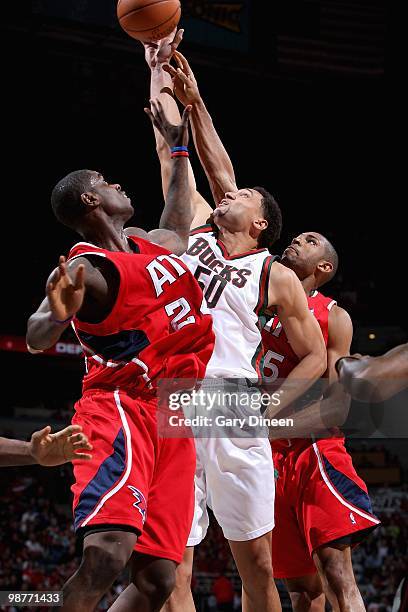 Dan Gadzuric of the Milwaukee Bucks reaches for a rebound over Marvin Williams and Al Horford of the Atlanta Hawks in Game Three of the Eastern...