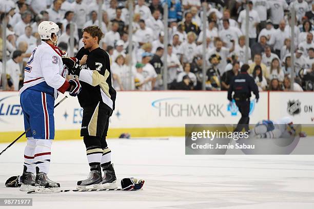 Travis Moen of the Montreal Canadiens squares off with Mark Eaton of the Pittsburgh Penguins at center ice as Andrei Markov of the Canadiens lies...