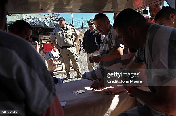 Detention officers watch as undocumented immigrants play cards in their tent at the Maricopa County Tent City Jail on April 30, 2010 in Phoenix,...