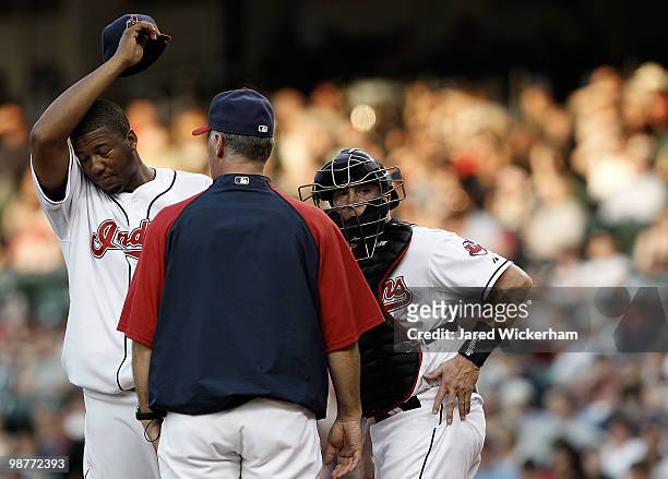 Fausto Carmona talks at the mound with Mike Redmond and pitching coach Tim Belcher of the Minnesota Twins during the game against the Cleveland...