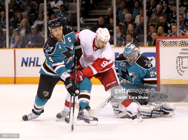 Rob Blake of the San Jose Sharks and Tomas Holmstrom of the Detroit Red Wings go for the puck while Evgeni Nabokov of the Sharks plays in the goal in...