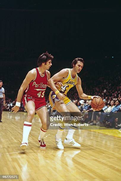 Jerry West of the Los Angeles Lakers moves the ball up court against Geoff Petrie of the Portland Trail Blazers during a game played circa 1971 at...