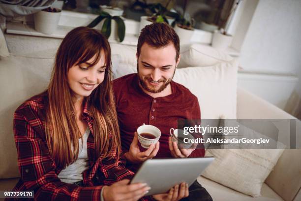 young couple watching funny videos on tablet and drinking coffee - human body part videos stock pictures, royalty-free photos & images