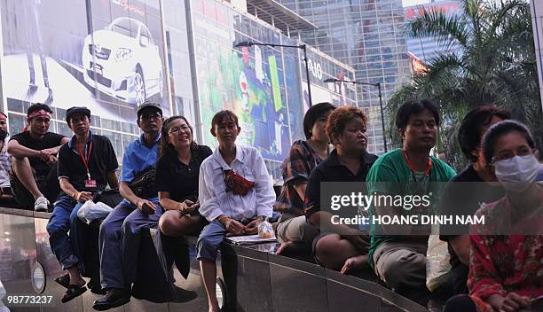 Thai Red-Shirt anti-government protesters sit listening to speeches next to a shopping center during a rally in the financial central district of...