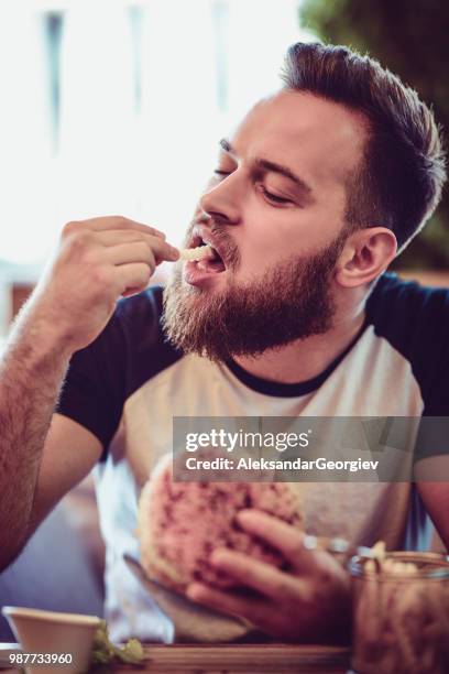 macho comiendo una hamburguesa en restaurante - male burger eating fotografías e imágenes de stock