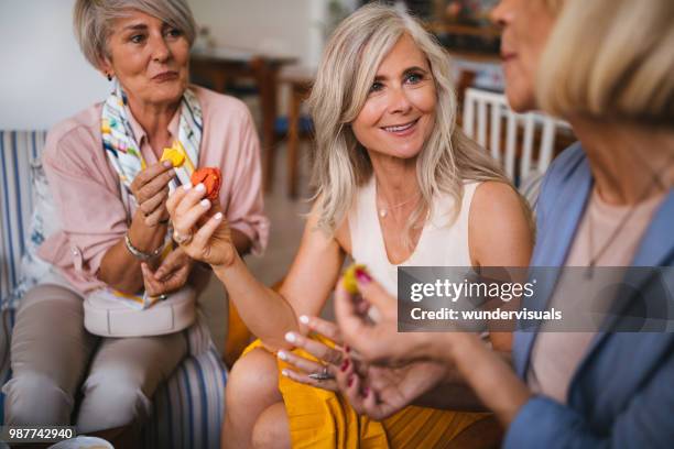 fashionable mature women having fun and eating colorful macarons - mature women eating stock pictures, royalty-free photos & images